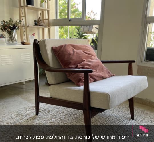 כרית ורודה על כורסה מרופדת בבד בהיר